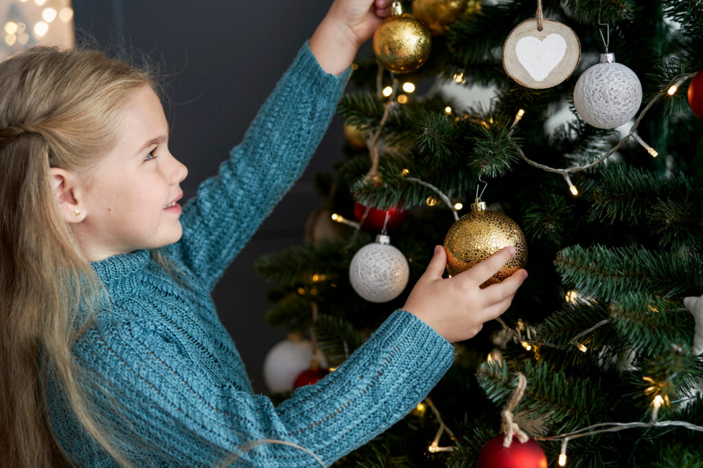 Kind schmückt Tannenbaum